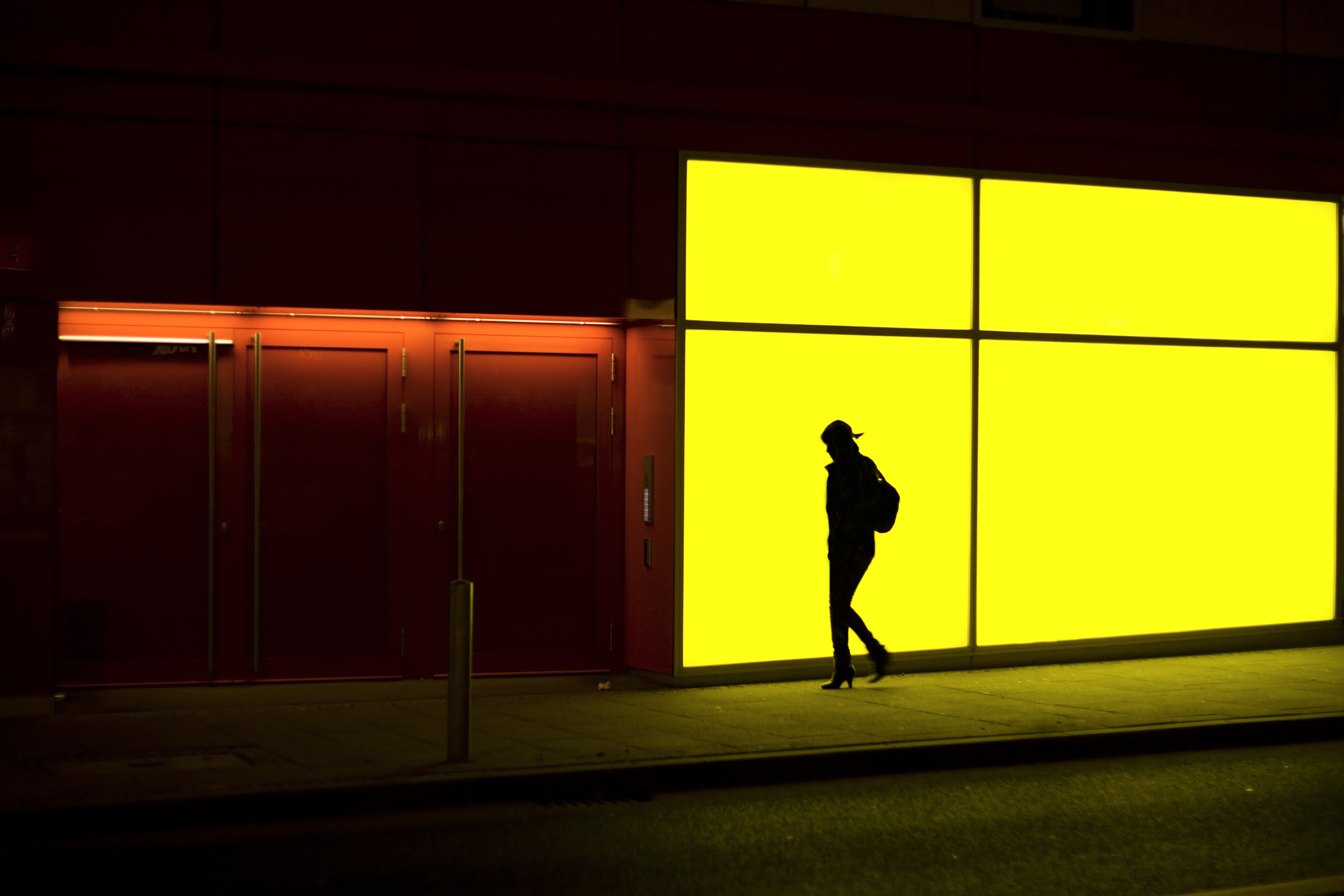 Young woman in front of a yellow illuminated wall