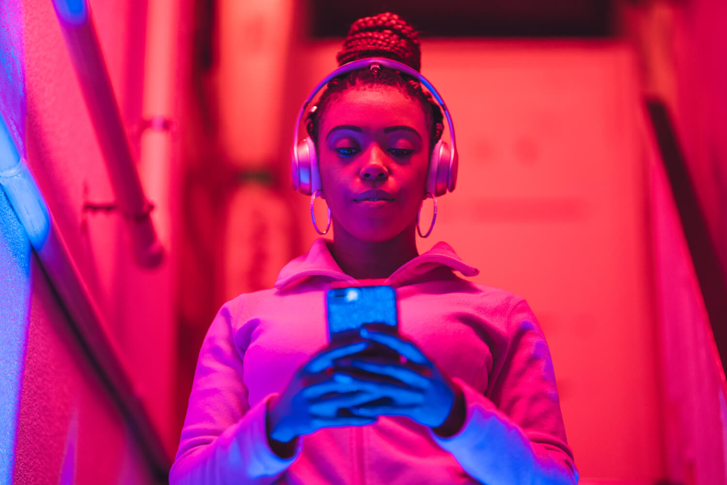 Portrait of young black woman listening to music under neon lights