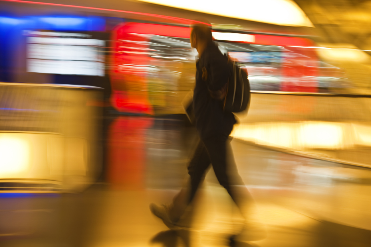 Man With Backpack Walking Past Illuminated Stores, Motion Blur