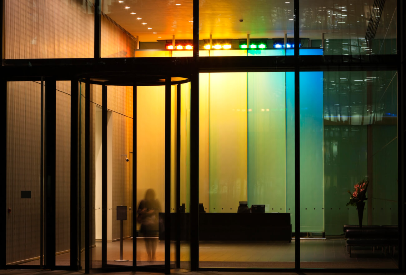 Businesswoman Exiting Illuminated Lobby Through Revolving Door