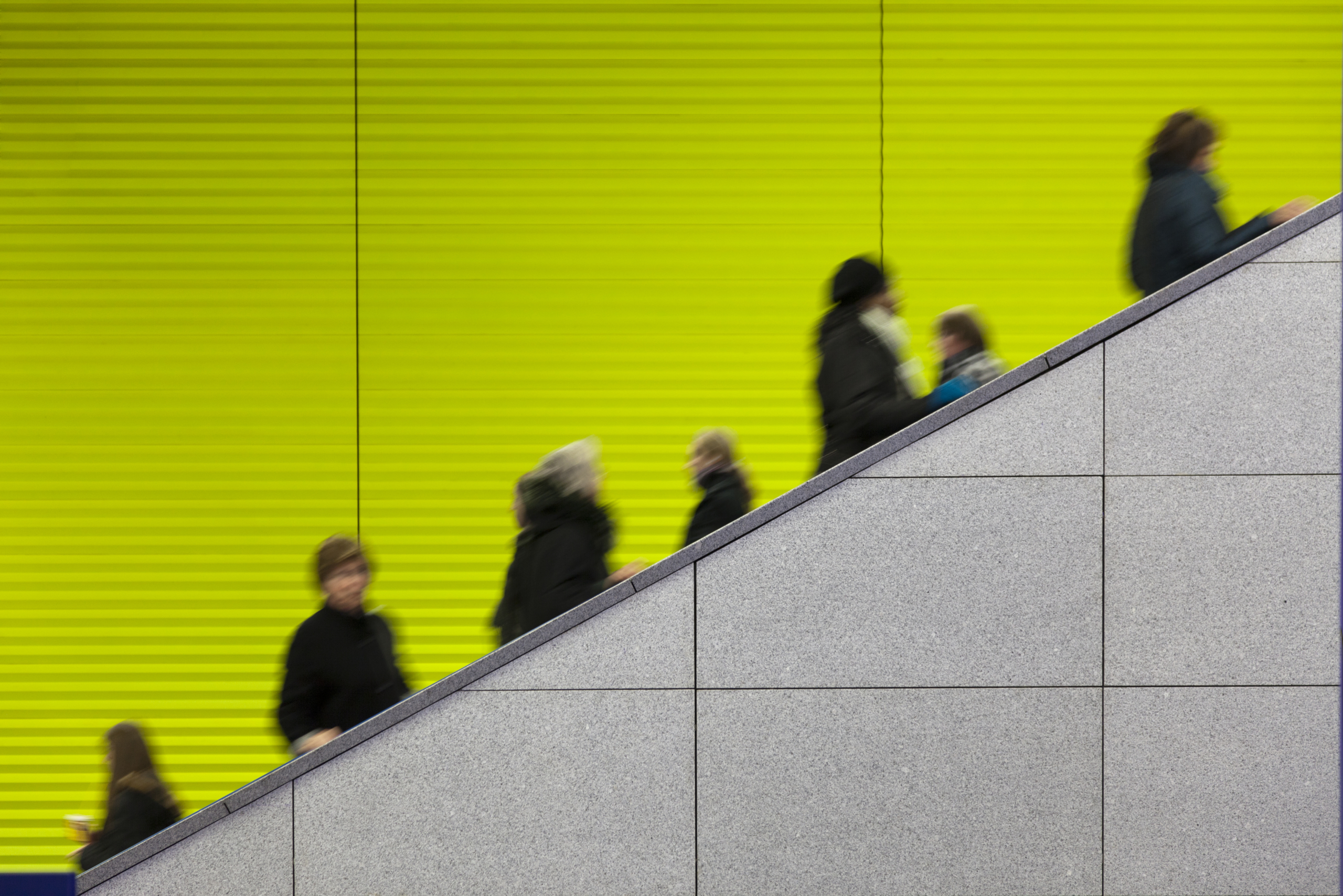Civilians riding an escalator with a green screen background
