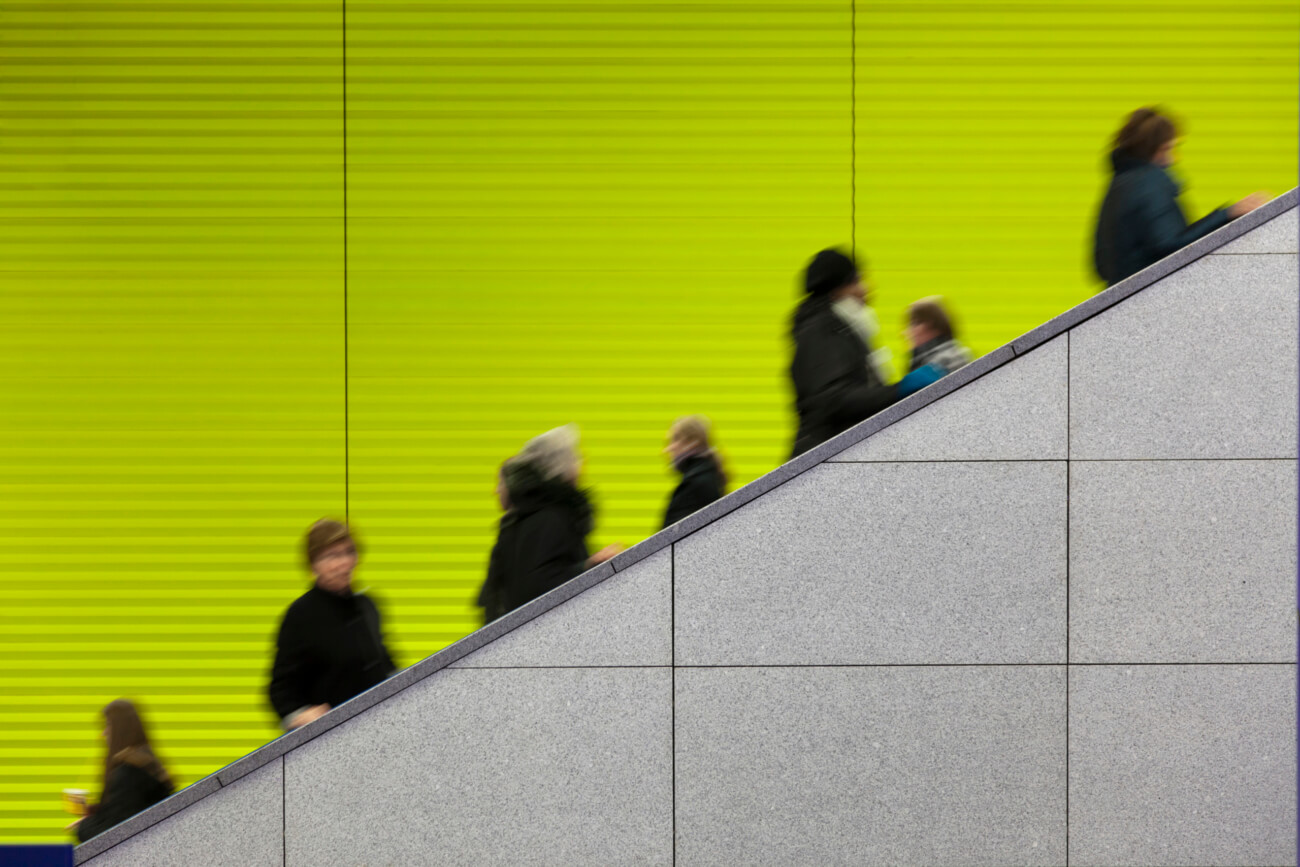 Civilians riding an escalator with a green screen background
